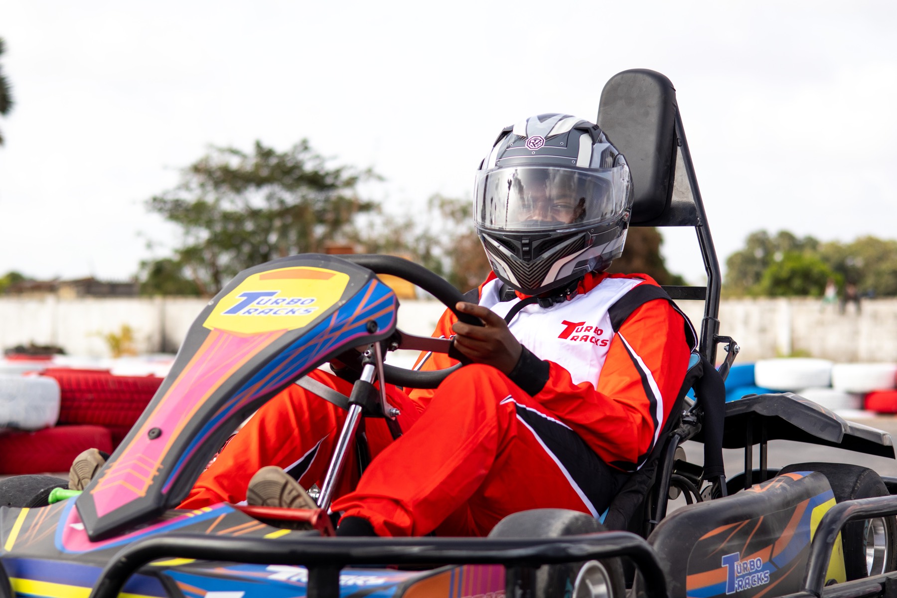 Driver in a Turbo Tracks kart wearing helmet and race suit